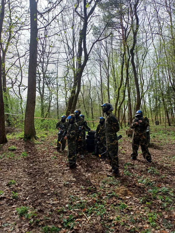 Paintball w lesie, uczestnicy w maskach