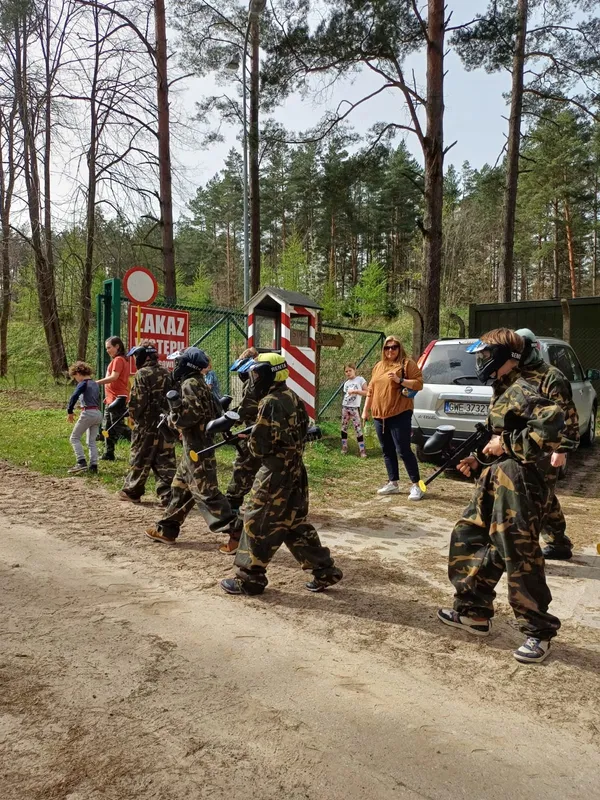 Uczestnicy paintballa w maskach idą na pole gry