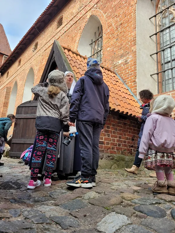 Dzieci słuchają przewodniczki na dziedzińcu zamku